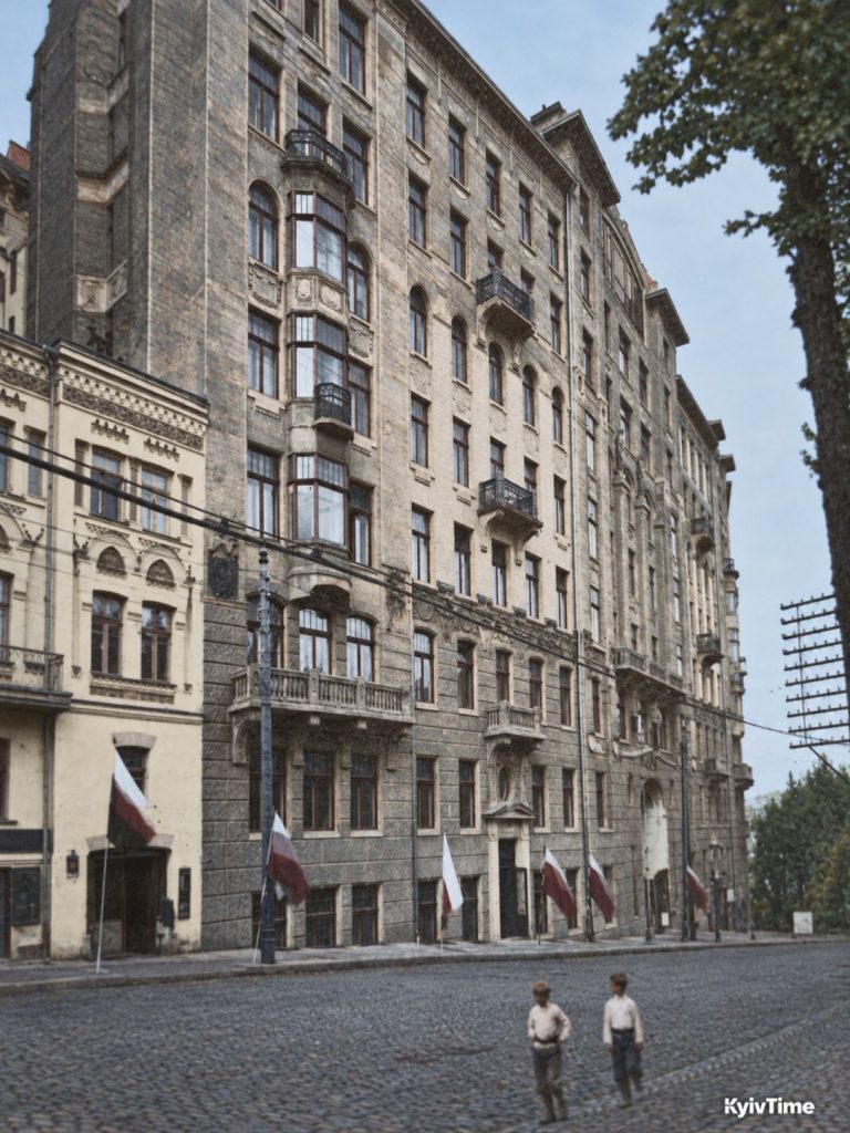 Фасад хмарочоса Гінзбурга з еркерами й балконами, біля будинку — двоє хлопчиків на бруківці.