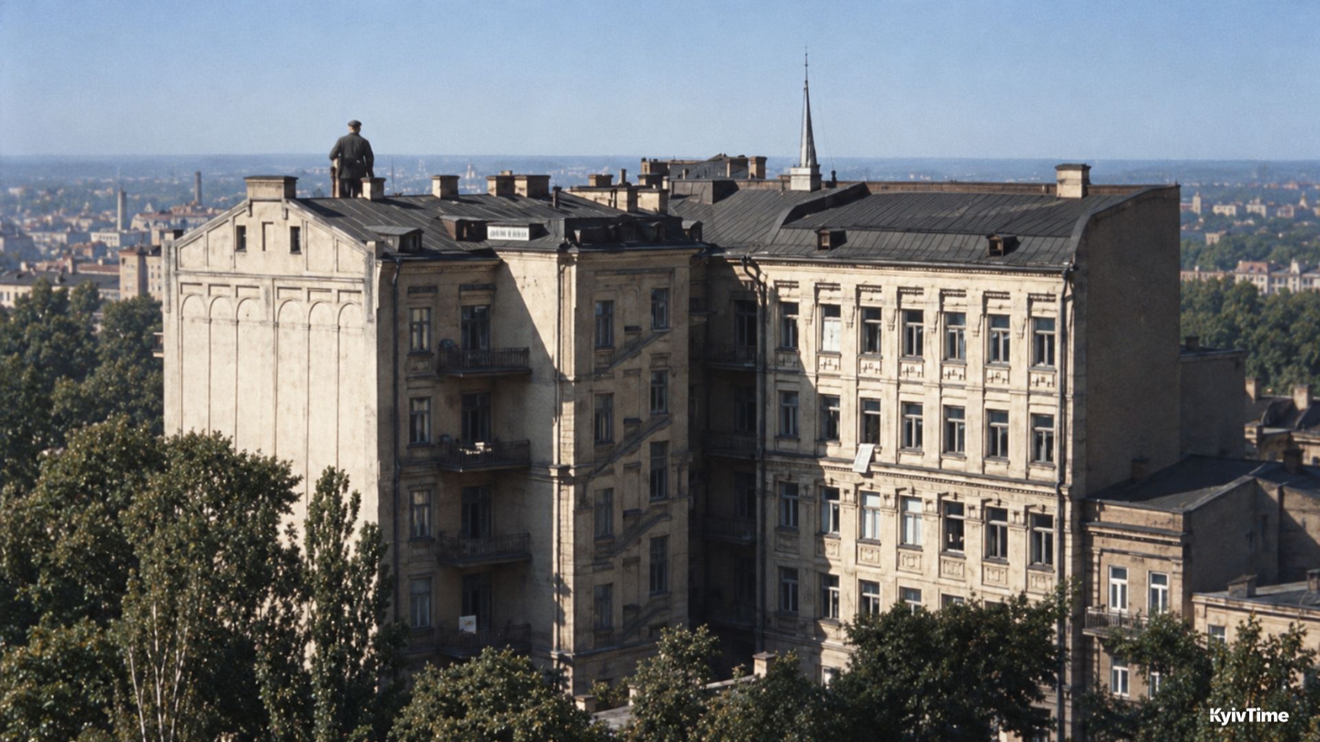 Багатоповерховий будинок із людиною на даху на тлі міської панорами.